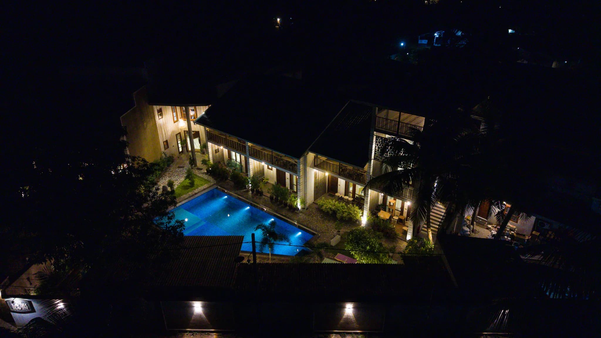 Night-time aerial view of the illuminated pool and courtyard