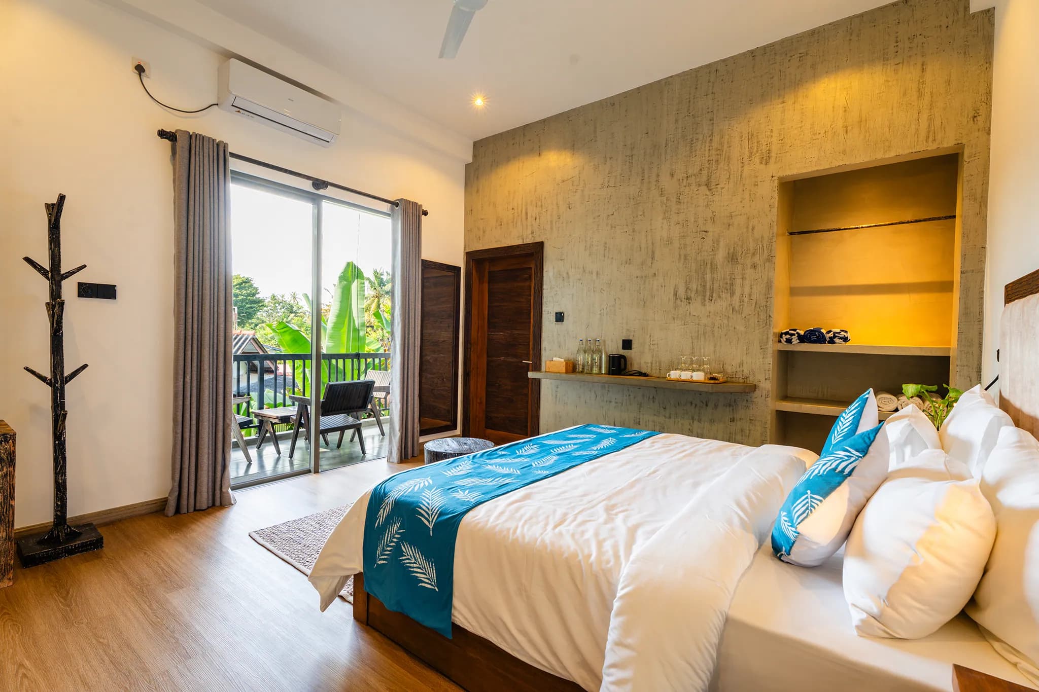 King bed with blue runner and doors to a sunny balcony