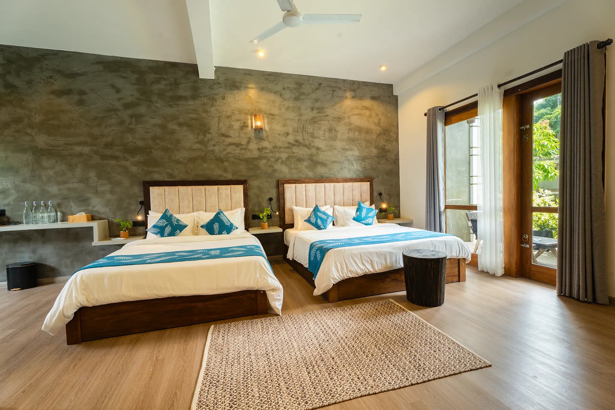 Two beds with blue runners beside a window