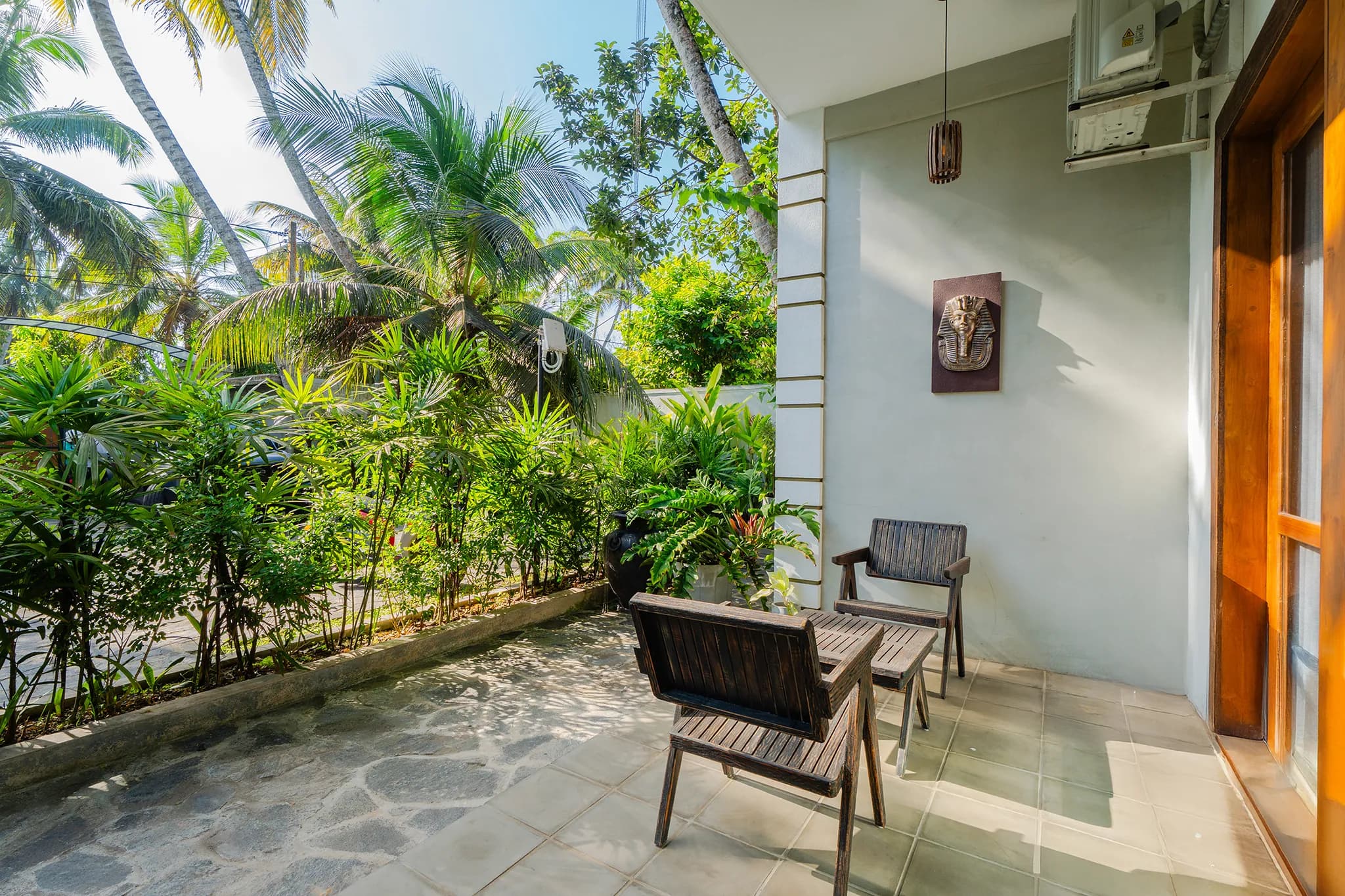 Stone-paved patio with chairs among tropical planting