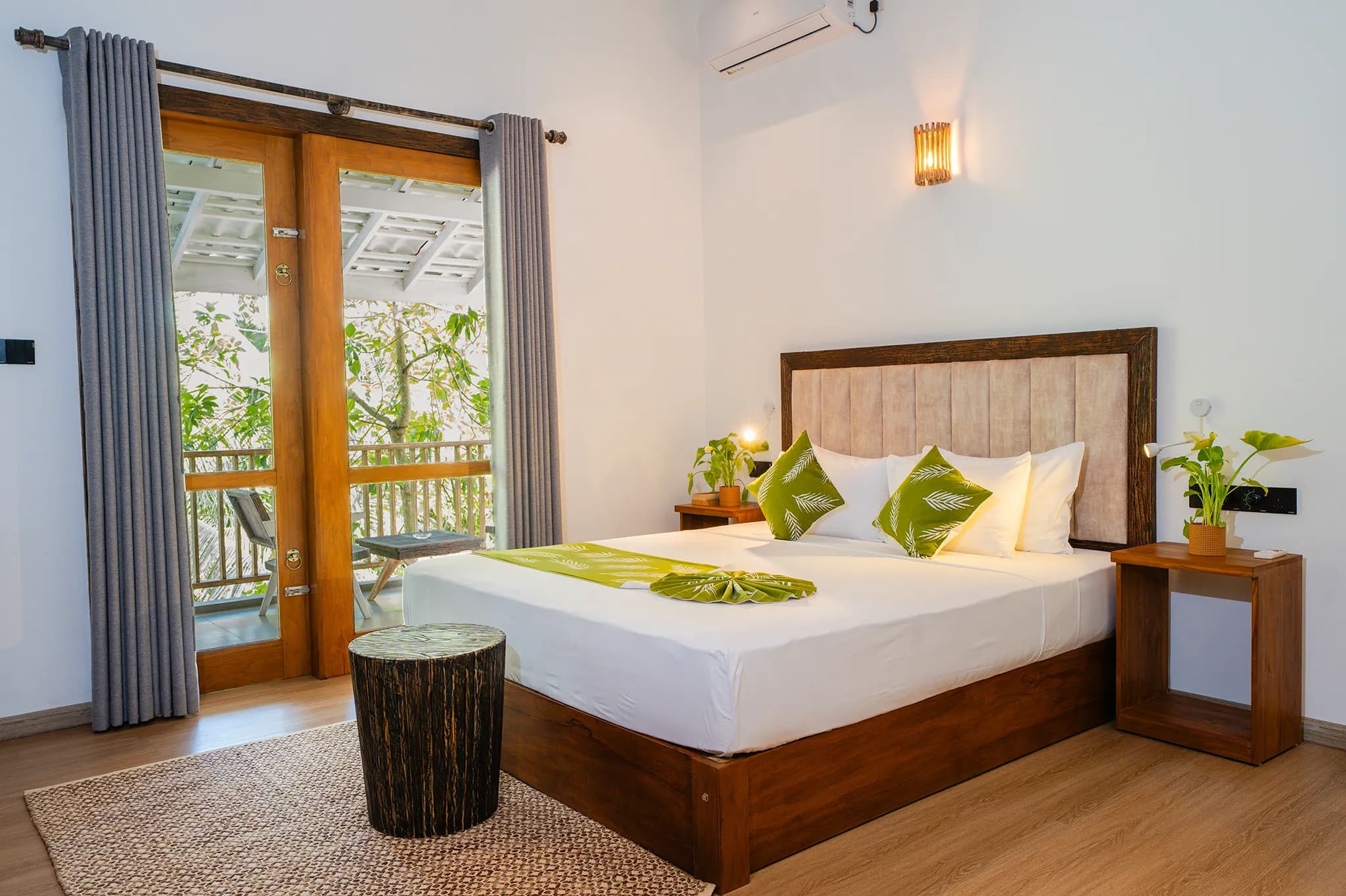 King bed with green cushions and balcony doors