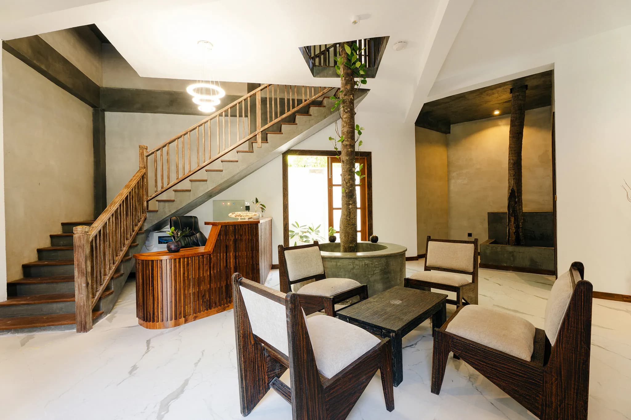 Lobby with timber staircase, rattan chairs and a tree growing through the floor
