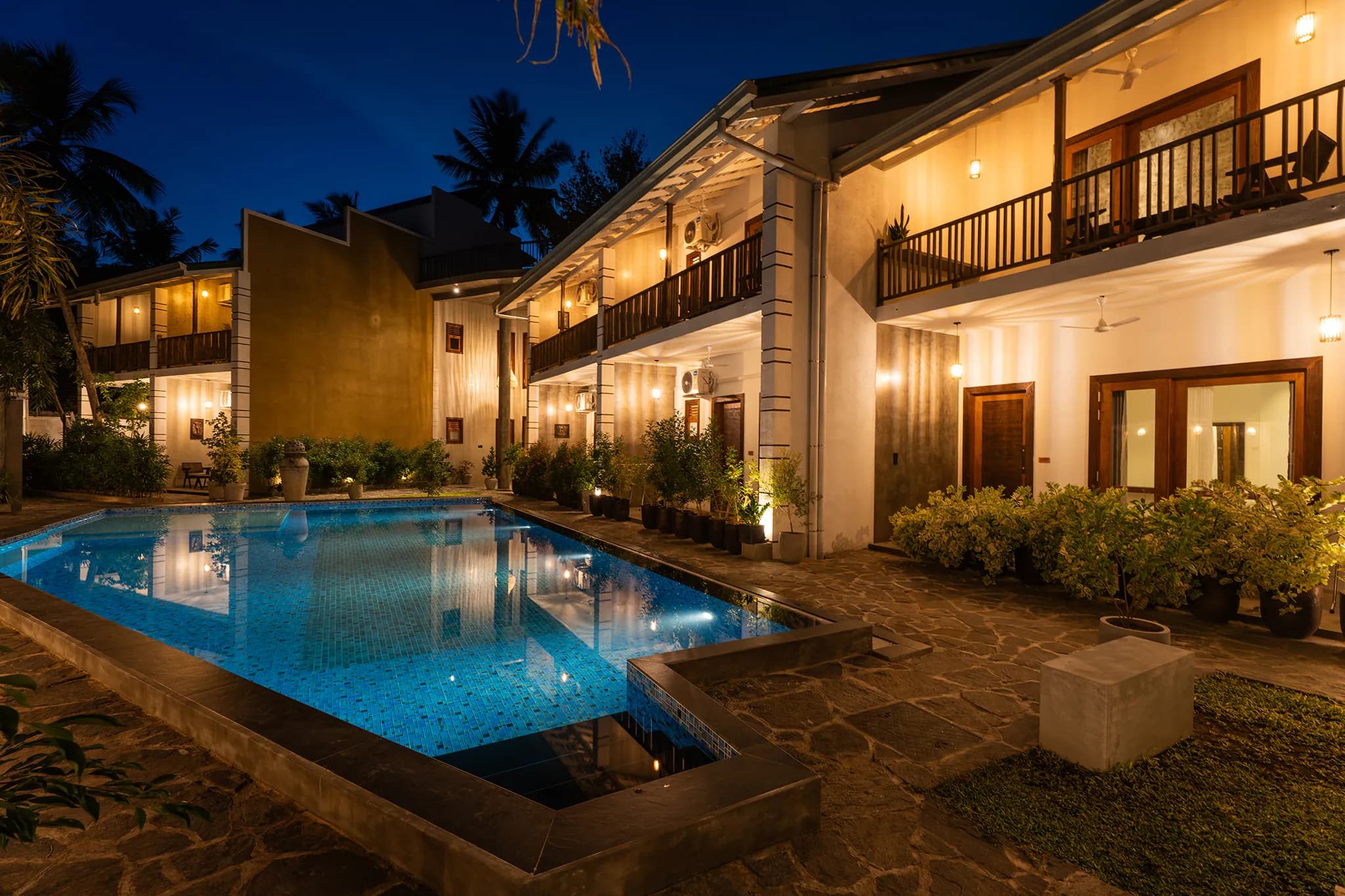 The Lavish Haven at dusk: the pool lit from below, balconies glowing under the gabled roofs